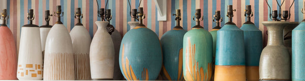  A dense row of ceramic table lamps in a rainbow of colors by ceramicist Natan Moss