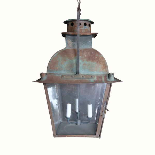 Hanging metal lantern with rounded glass panels, verdigris patina, and three candle slots