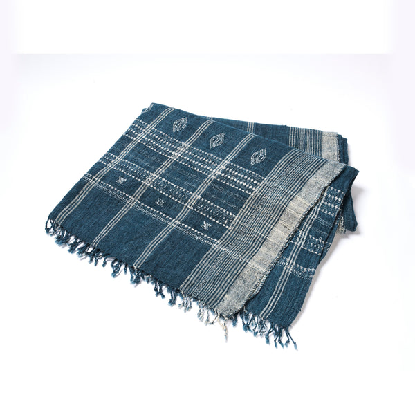 Folded indigo bedcover with grid pattern, small motifs, fringed corners