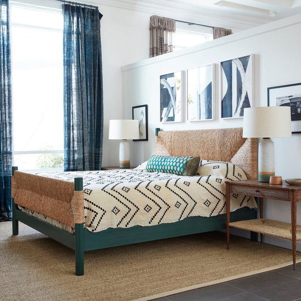 Perriand Rush Bed with light rush headboard and dark wood legs, striped bedding