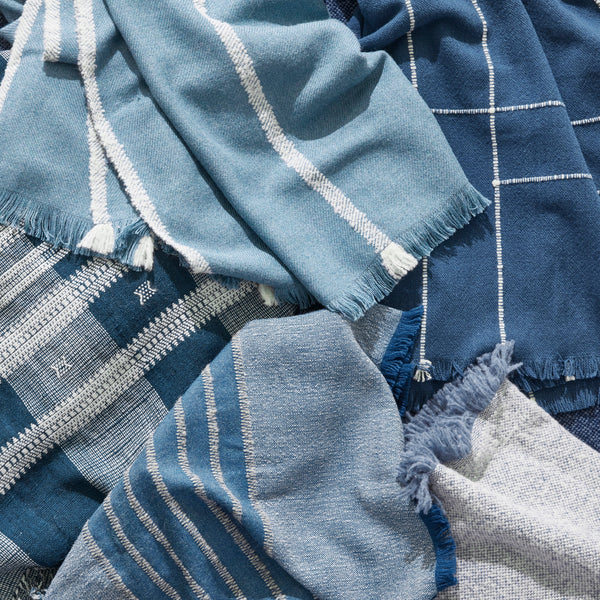 Indigo Indian bedcover close-up: blue fabric with white stripes and tassel fringe