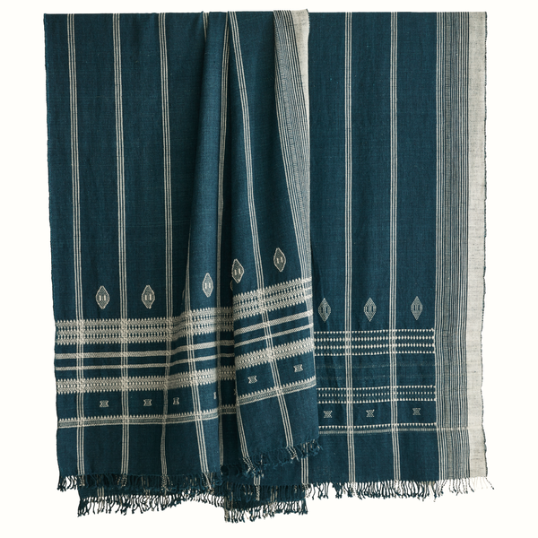 Indigo Indian bedcover showing folded corner, vertical stripes, white motifs, fringed hem