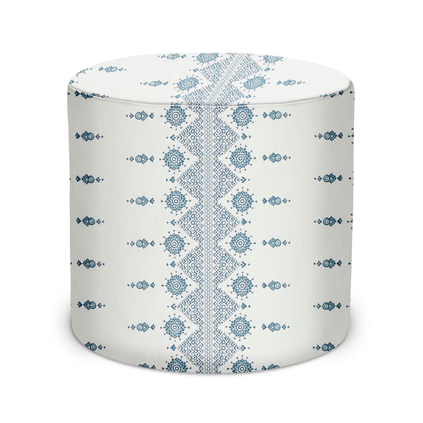 Indoor pouf ottoman with blue geometric medallion fabric on white, rounded cylinder.