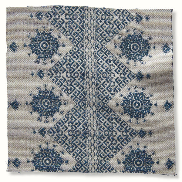 Indigo outdoor pillow cover with symmetrical geometric medallion pattern on natural fabric