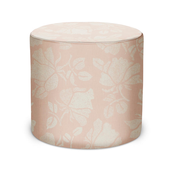 Pink and white cylindrical upholstered pouf with floral pattern top