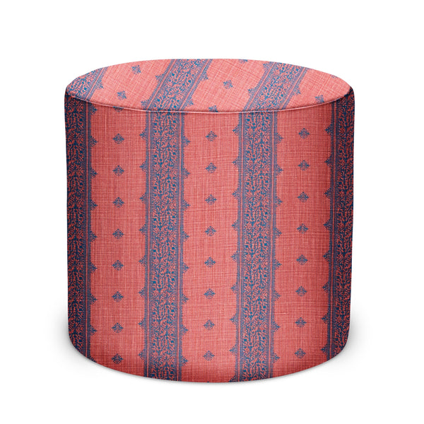 Round indoor pouf in coral and indigo geometric fabric, cylindrical top.