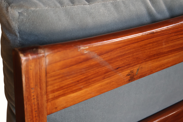 Wooden armchair close-up: reddish-brown armrest rail with light blue cushion