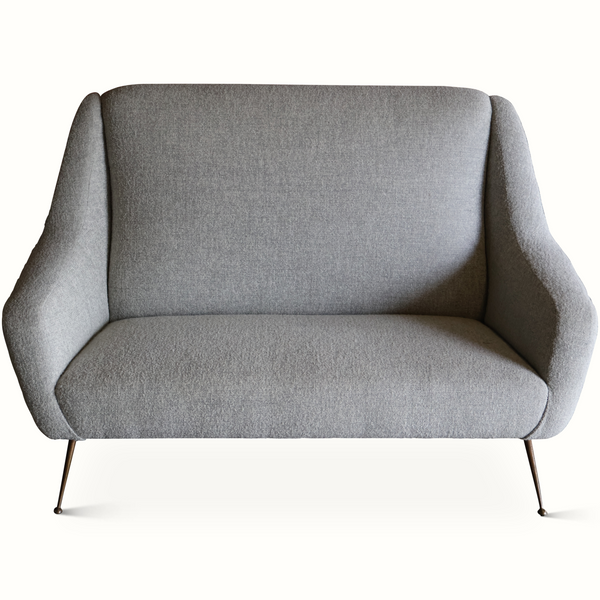 Light gray upholstered mid-century settee with curved arms and slender black legs.