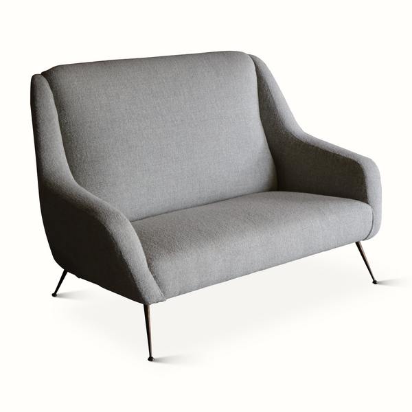 Light gray upholstered mid-century settee with curved arms, wide seat, and black legs.