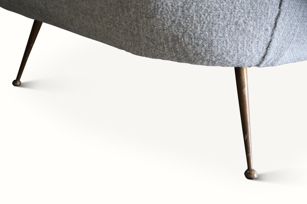 Dark metal legs attached to a light gray upholstered mid-century settee base.