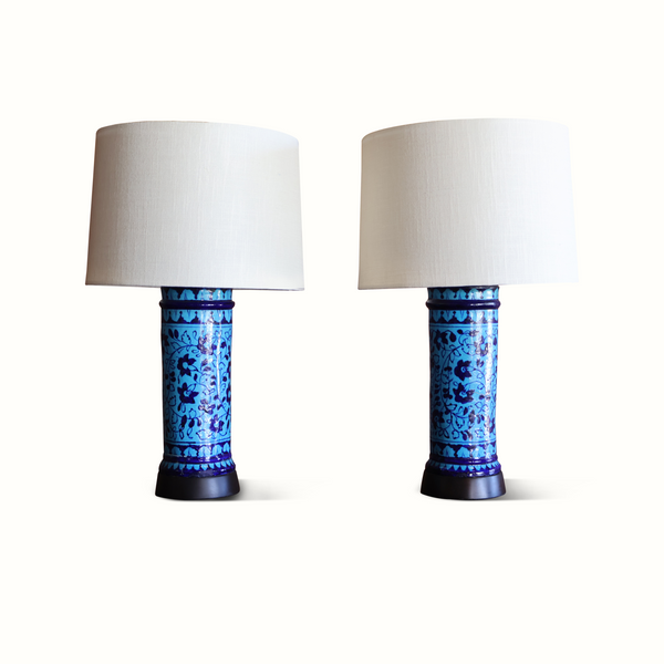 Pair of blue pottery table lamps with white fabric shades, angled view