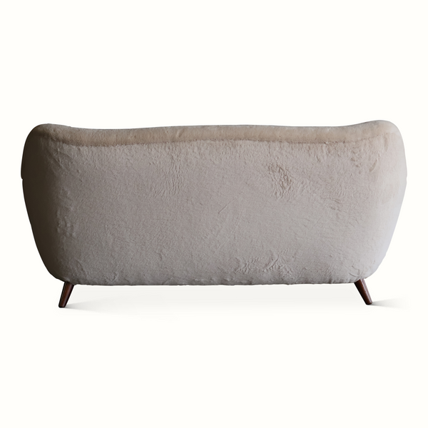 Back view of light gray upholstered sofa with curved back and dark wooden feet.