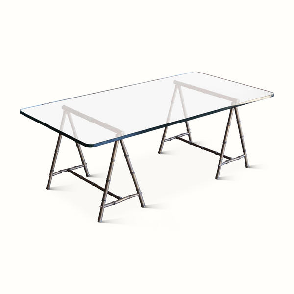 Coffee table with clear glass top and trestle legs with bamboo-style metal detailing