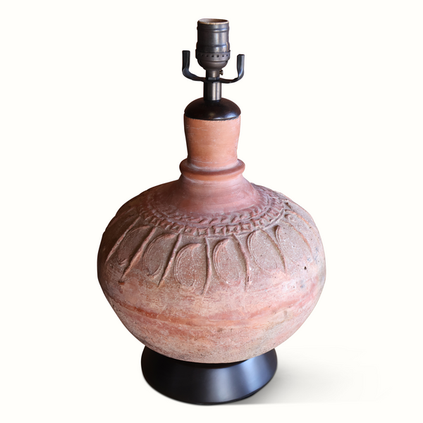 Pottery table lamp with terracotta base, carved relief, metal socket, and tan fabric shade