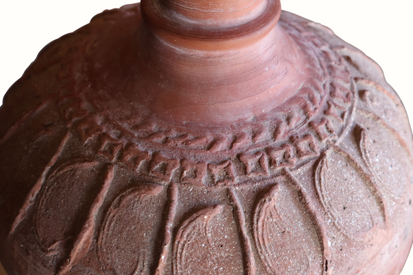 Ceramic lamp base close-up with carved relief pattern and speckled terracotta finish