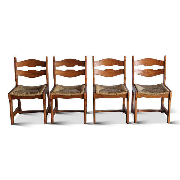 Set of four wooden dining chairs with wavy back slats, armrests, and upholstered cushion seats