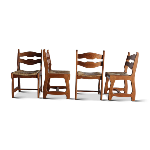 Set of four wooden dining chairs with wavy backrest, armrests, and cushioned seats in view