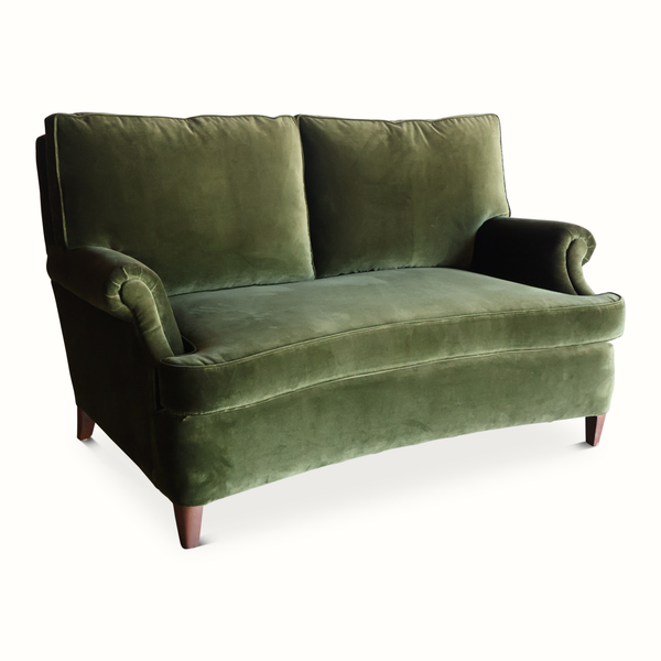 Green velvet French-style sofa angled view with tufted back, rolled arms, tapered legs