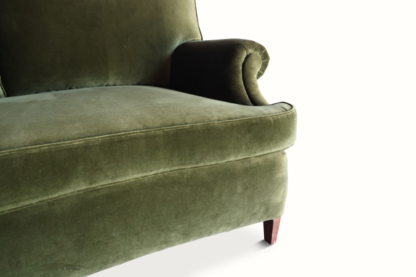Green velvet sofa arm and seat detail with rolled arm and stitched seam trim