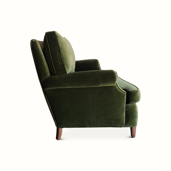 Green velvet French-style sofa side view with rolled arm, tufted backrest, wooden legs
