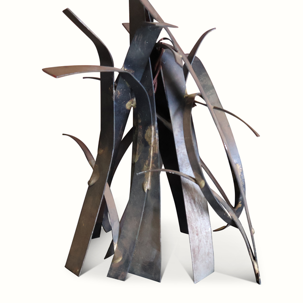 Brutalist metal lamp detail with curved dark blades and weathered patina