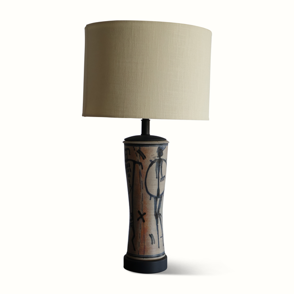 Pottery table lamp with beige fabric shade and blue abstract figures on ceramic body