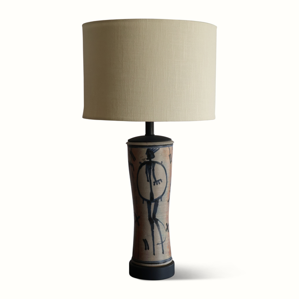 Pottery table lamp with beige fabric shade and blue abstract figure ceramic base