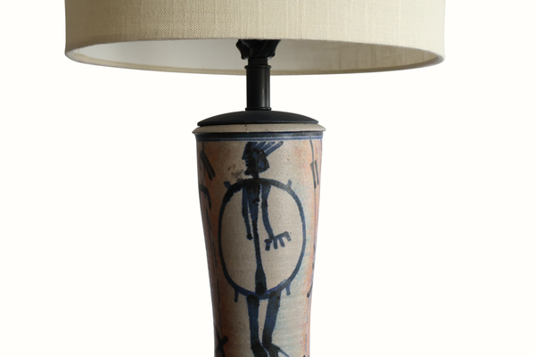 Close-up of pottery table lamp base with blue abstract figure and black mounting top