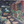 Oil painting close-up of garden walkway with flowers, greenery, and a red building