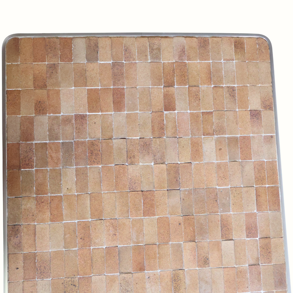 Rounded-edge tile coffee table top close-up with terracotta mosaic and pale grout