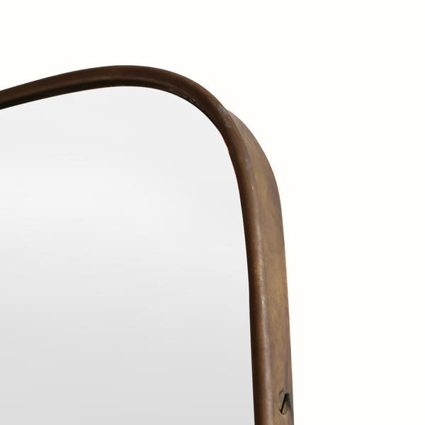 Wall mirror frame corner detail with curved brass-toned trim