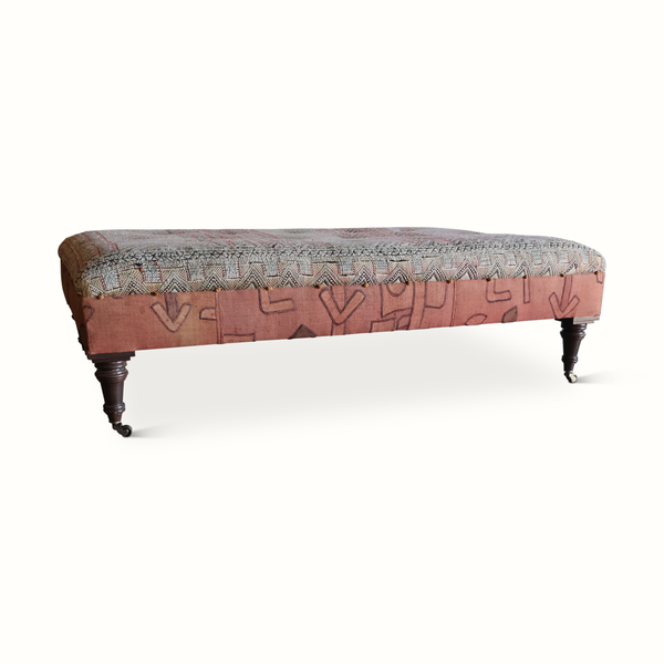Tufted ottoman with patterned top, gray and rust fabric, dark wood legs