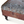Tufted ottoman corner detail with patterned fabric top and dark carved wood leg