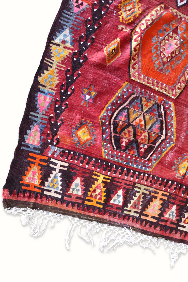 Turkish kilim rug with burgundy weave, hexagon medallions, multicolor accents and fringed hem.