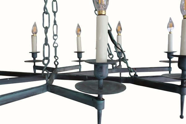 Close-up iron chandelier centerpiece with round base, hanging chains, and candelabra bulbs