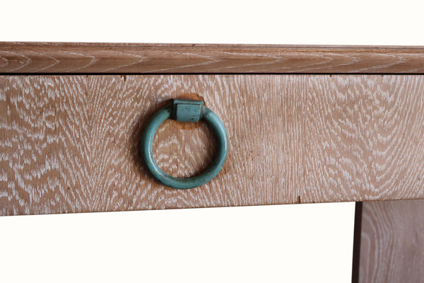Drawer front of a cerused oak console with teal ring pull and wood grain texture