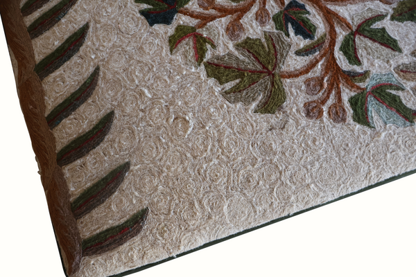 Beige ottoman cover detail with textured fabric, branch pattern, and dark wood side panel