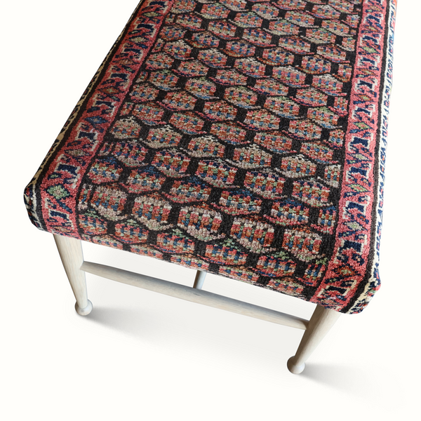 Geometric rug fabric on bench top in red, blue, and cream with patterned border