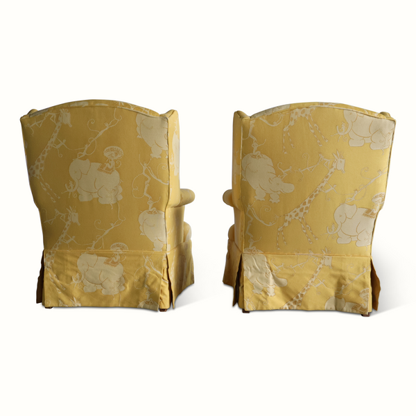 Pair of yellow wingback armchairs from behind/side, upholstered with light animal circus print