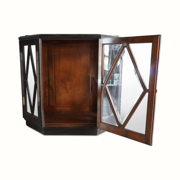 Corner view of dark wood vitrine cabinet with hinged faceted glass door and interior