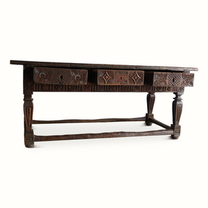 Carved oak table side view with geometric carvings on apron and turned legs