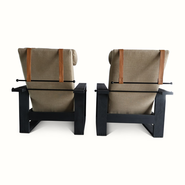 Pair of beige reclining armchairs with tan straps and dark wood frames