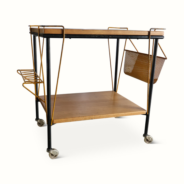 Bar cart with wood work surface, black frame, brass-toned side basket, caster wheels