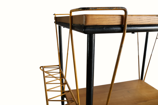 Bar cart corner detail: black legs, brass frame, wire side rack, wood shelf