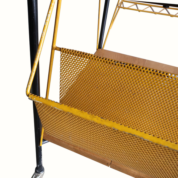 Perforated brass-toned basket on bar cart, mounted to black-and-brass frame