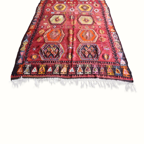 Turkish kilim rug, burgundy central motifs, dark border with colorful zigzags and fringe.