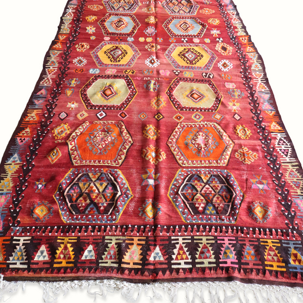 Turkish kilim rug with burgundy field, multicolor geometric medallions and fringed border.