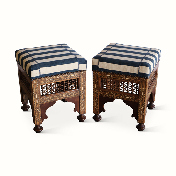 Pair of inlaid Moorish stools from front view: striped cushions and ornate carved panels