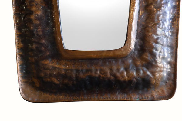 Vintage copper mirror frame close-up, textured lower border with arched cutout
