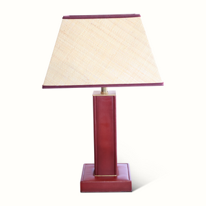 Red leather table lamp with beige fabric shade and dark trim, brass accents.